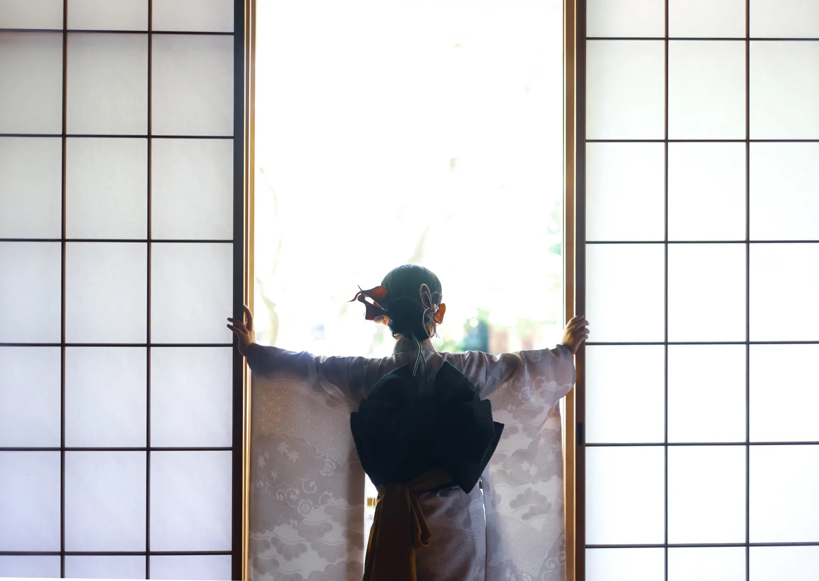 障子を両手で開けて、庭を眺めるお子さまの後ろ姿
