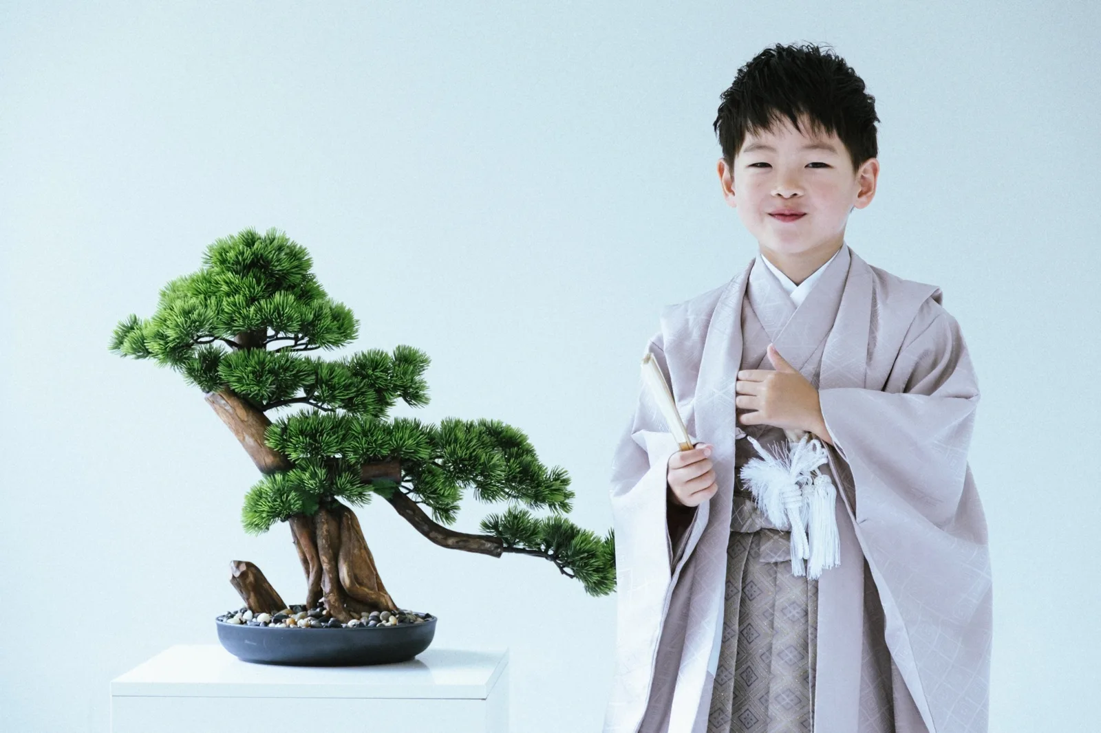 盆栽の横に立つ、袴姿の男の子