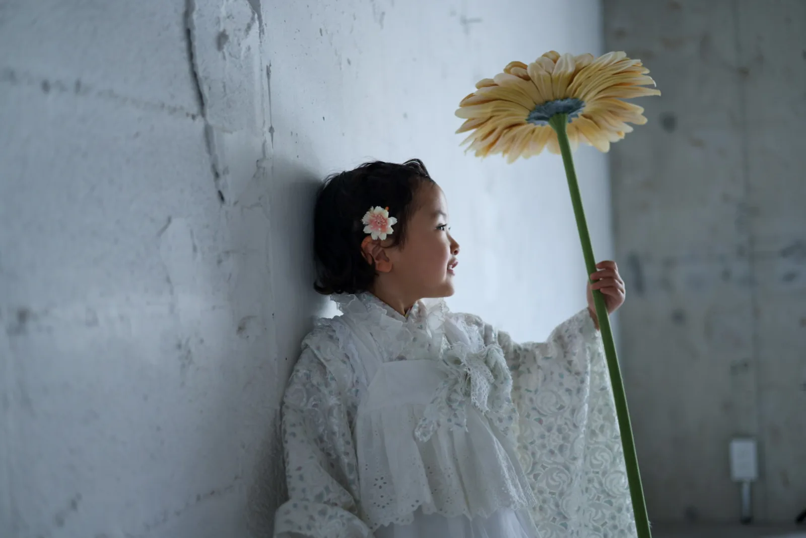 大きな花を見上げる、3歳の女の子の横顔
