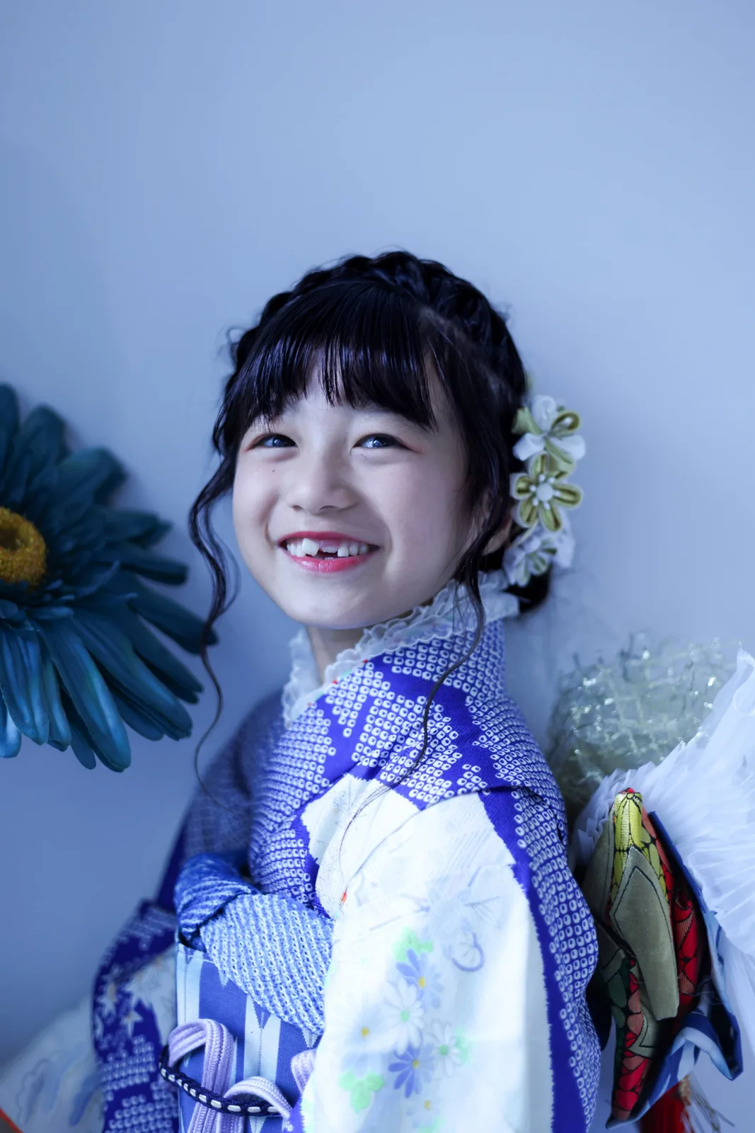 花の飾りの前で笑う、七五三の女の子